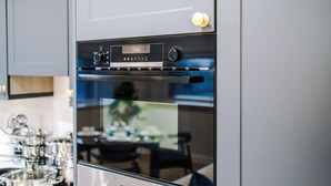 Moderni keittiö, jossa on Bosch-uuni, ruokailutila pöydän ja tuolien kera sekä näkymä puutarhaan.