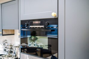 A modern kitchen with a Bosch oven, a dining area with a table and chairs, and a view of a garden. - Modern 2BR Apartment Leeds Centre (Leeds)