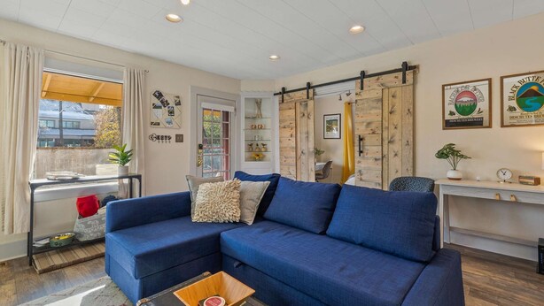 A living room with a blue sofa, a wooden coffee table, a bookshelf, and a sliding barn door.