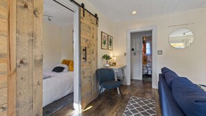 A room with a bed, a desk, a chair, a couch, and a bathroom visible through an open door.
