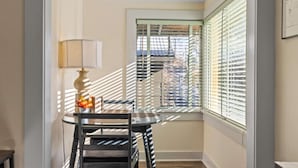 A dining area with a table and chairs, a lamp, and a window with blinds.