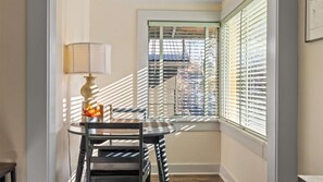 Ein Essbereich mit Tisch und Stühlen, einer Lampe und einem Fenster mit Jalousien.