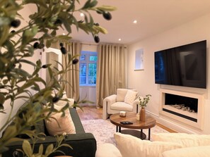 Una sala de estar con sofá, sillón, mesa de centro y chimenea.