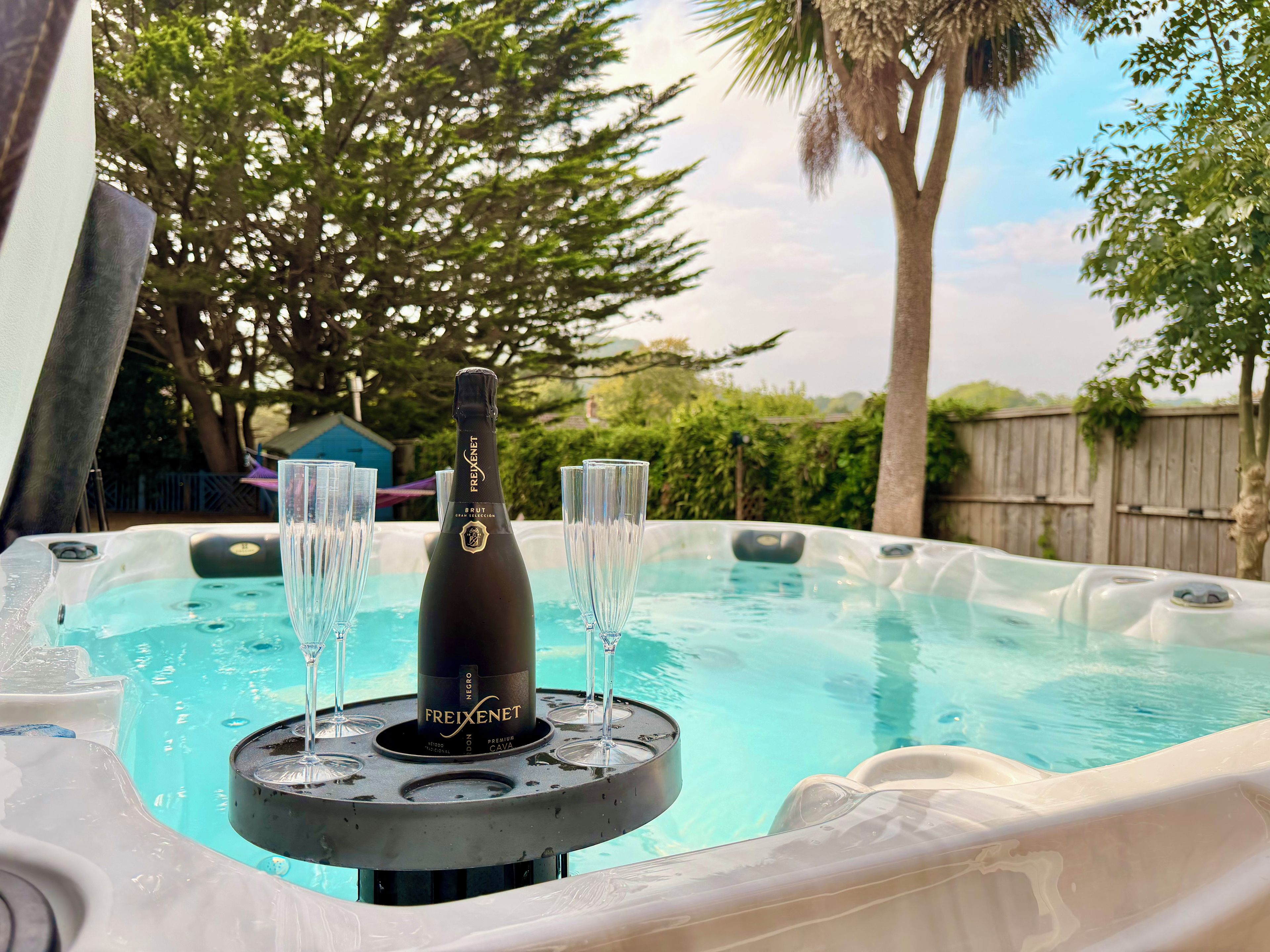 A hot tub with a bottle of Freixenet Brut Cava champagne and glasses.