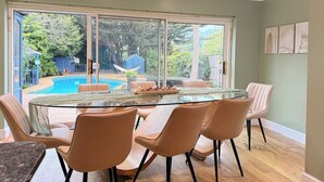 En matplats med ett glasbord, sex stolar och utsikt över en swimmingpool.