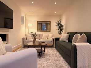 A living room with a sofa, armchair, and a coffee table. - Palm House | Pool, Hot Tub | South Downs (Worthing)