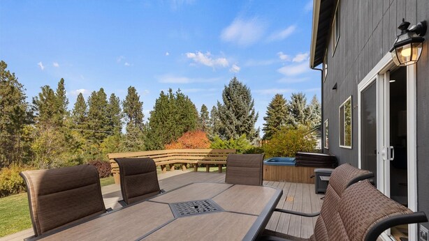 Eine Terrasse im Freien mit Tisch, Stühlen, einem Whirlpool und einer Holzbank.