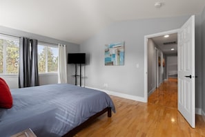 A bedroom with a bed, a TV, a painting, and a hallway leading to another room. - New! Beautiful 5 Bedroom Retreat | Hot Tub | Backyard (Bend)