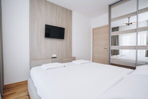 A hotel room with a bed, a TV mounted on the wall, a wooden wardrobe, and a mirror with a bunk bed. - Status M Apartments 205 (Becici)