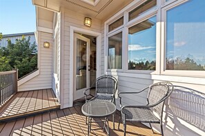 Eine überdachte Terrasse mit zwei Metallstühlen und einem Tisch, mit Blick auf eine verschneite Landschaft durch große Fenster.