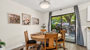 A dining area with a round wooden table, four chairs, and a ceiling fan.