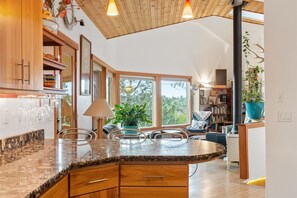 Eine moderne Küche mit einer Granitabdeckung, Holzschränken und einem großen Fenster mit Blick auf Bäume und ein Haus.