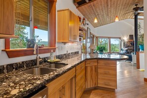 Eine moderne Küche mit Granit-Arbeitsplatten, Holzschränken und einer integrierten Kücheninsel.