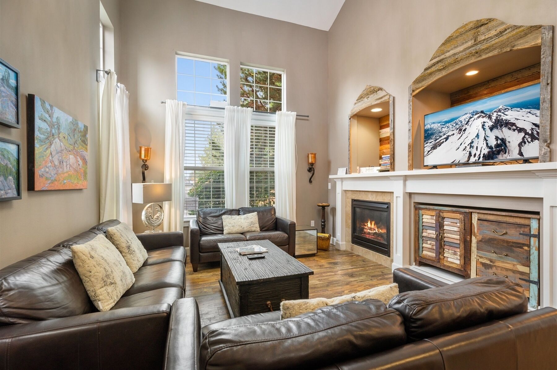 A living room with leather sofas, a fireplace, and artwork on the walls.