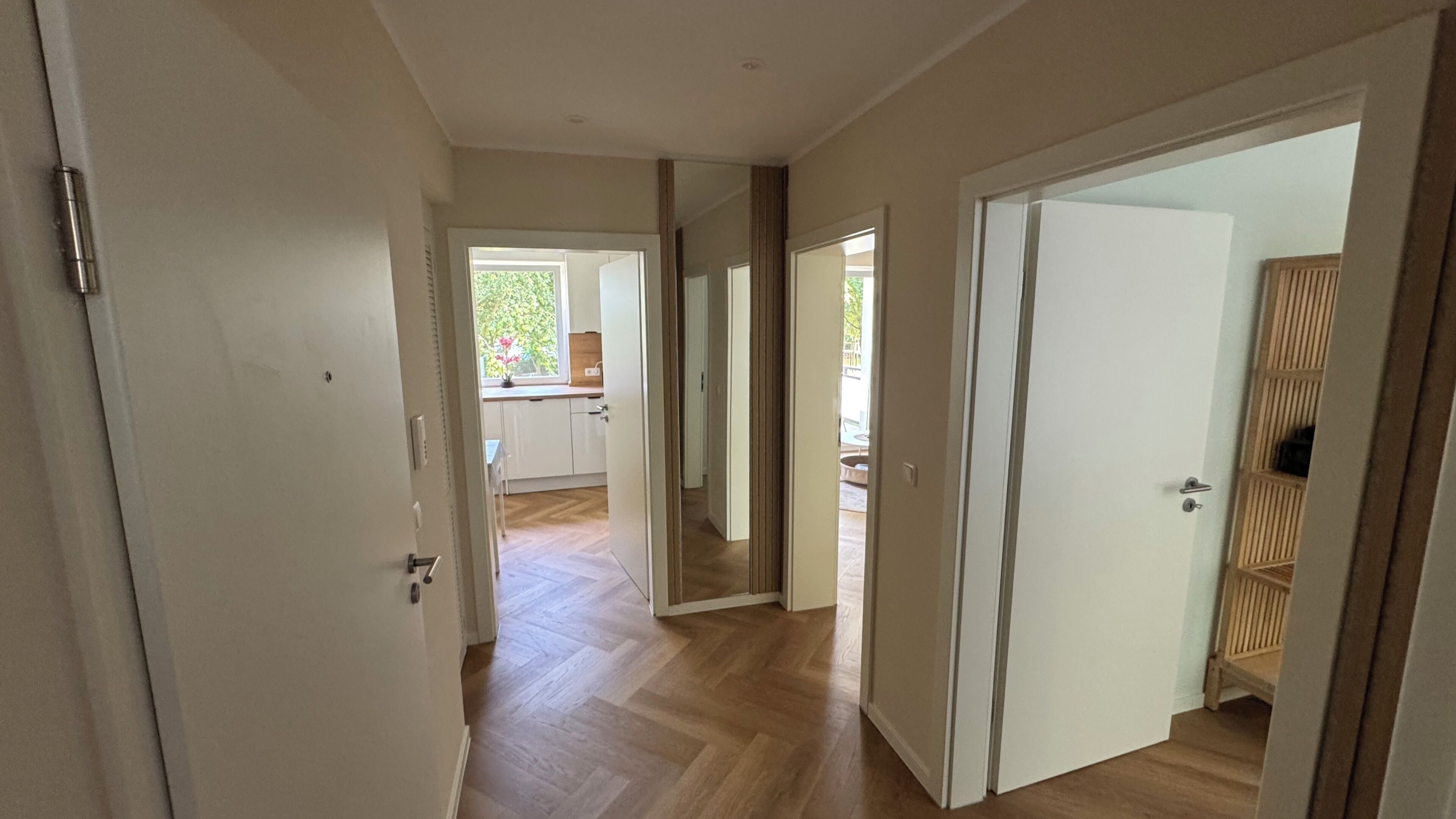 Een gang met houten vloeren, witte wanden en deuren naar verschillende kamers.