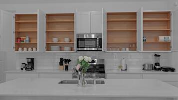 Une cuisine moderne avec des meubles blancs, une cuisinière en acier inoxydable et un îlot central doté d’un évier.