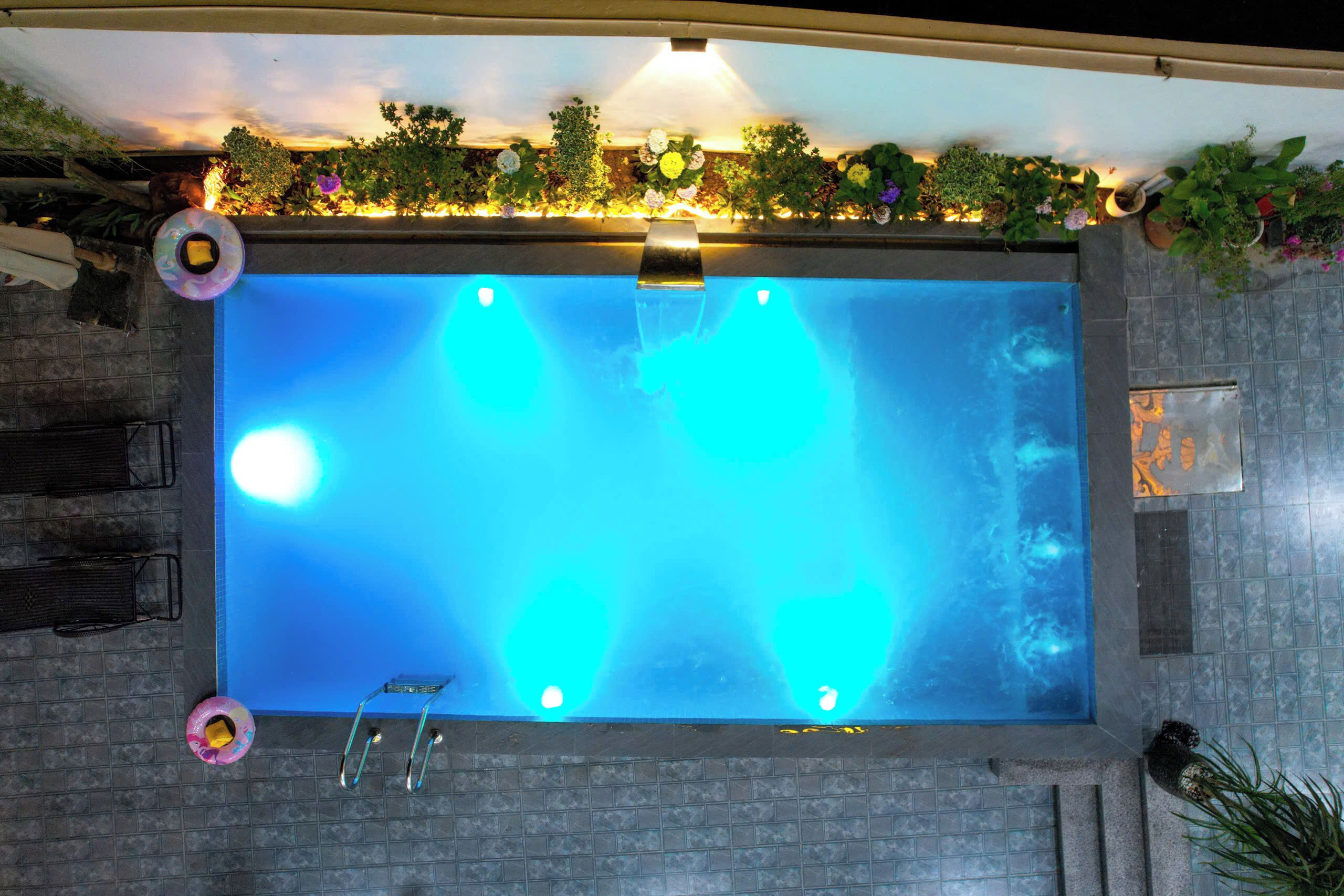 Una piscina rectangular con borde de azulejos, rodeada por un patio de ladrillo.