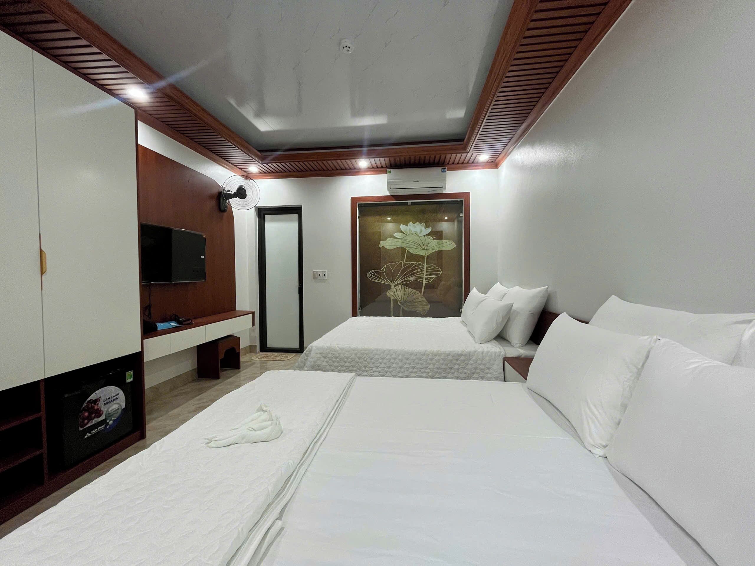 Habitación de hotel con dos camas, televisión, espejo y aire acondicionado instalado en la pared.