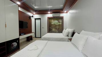 Habitación de hotel con dos camas, televisión, espejo y aire acondicionado instalado en la pared.