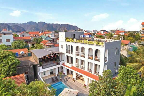 A hotel with a pool, balconies, and a view of mountains. - Tam Coc Lotus Homestay (Nam Hoa Lu)