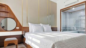 Quarto com cama, mesa de cabeceira, espelho e zona de duche.