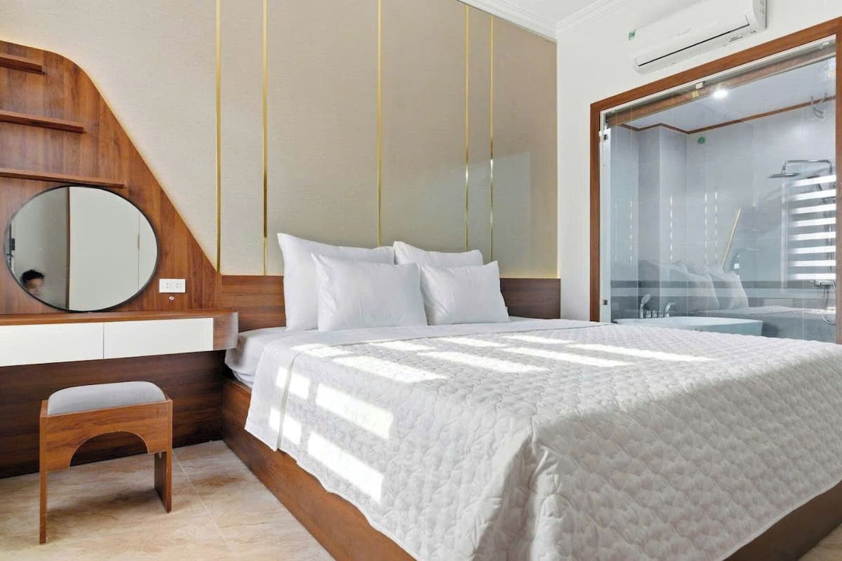Une chambre à coucher comprenant un lit, une table de chevet, un miroir et un espace douche.