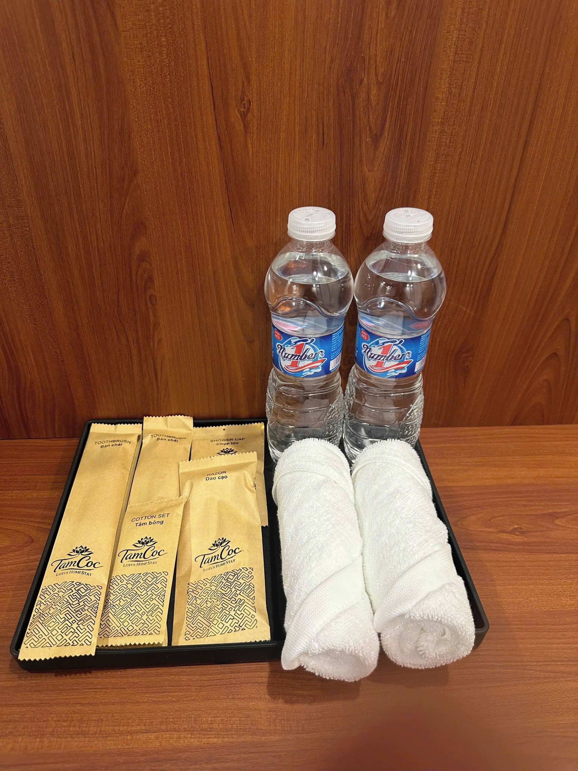 Ein Tablett mit zwei Wasserflaschen, vier Handtüchern und vier Sets Pflegeprodukte.