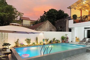 A swimming pool with a view of a sunset, surrounded by potted plants and outdoor furniture. - Tam Coc Lotus Homestay (Nam Hoa Lu)