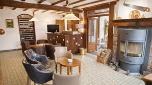 A cozy interior with a fireplace, seating area, and a wine rack. - Hôtel La Ferme de Sy (Ferrières)