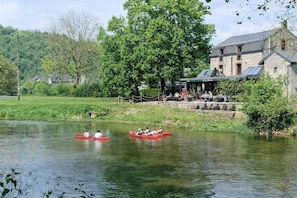 A riverside setting with a riverside restaurant and a stone building with a covered patio.