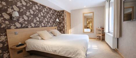 A bedroom with a large bed, bedside tables, a mirror, and a desk.