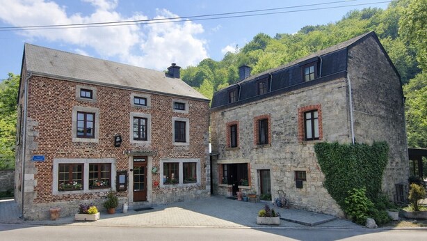 A two-story building with a brick facade and stone accents, featuring a reception area and multiple windows. - Hôtel La Ferme de Sy (Ferrières)