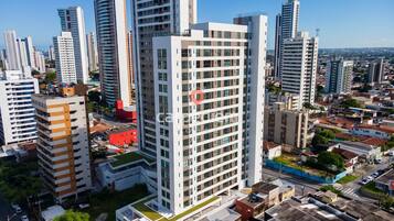 Um edifício alto com vários andares, cercado por outros edifícios altos em um ambiente urbano.