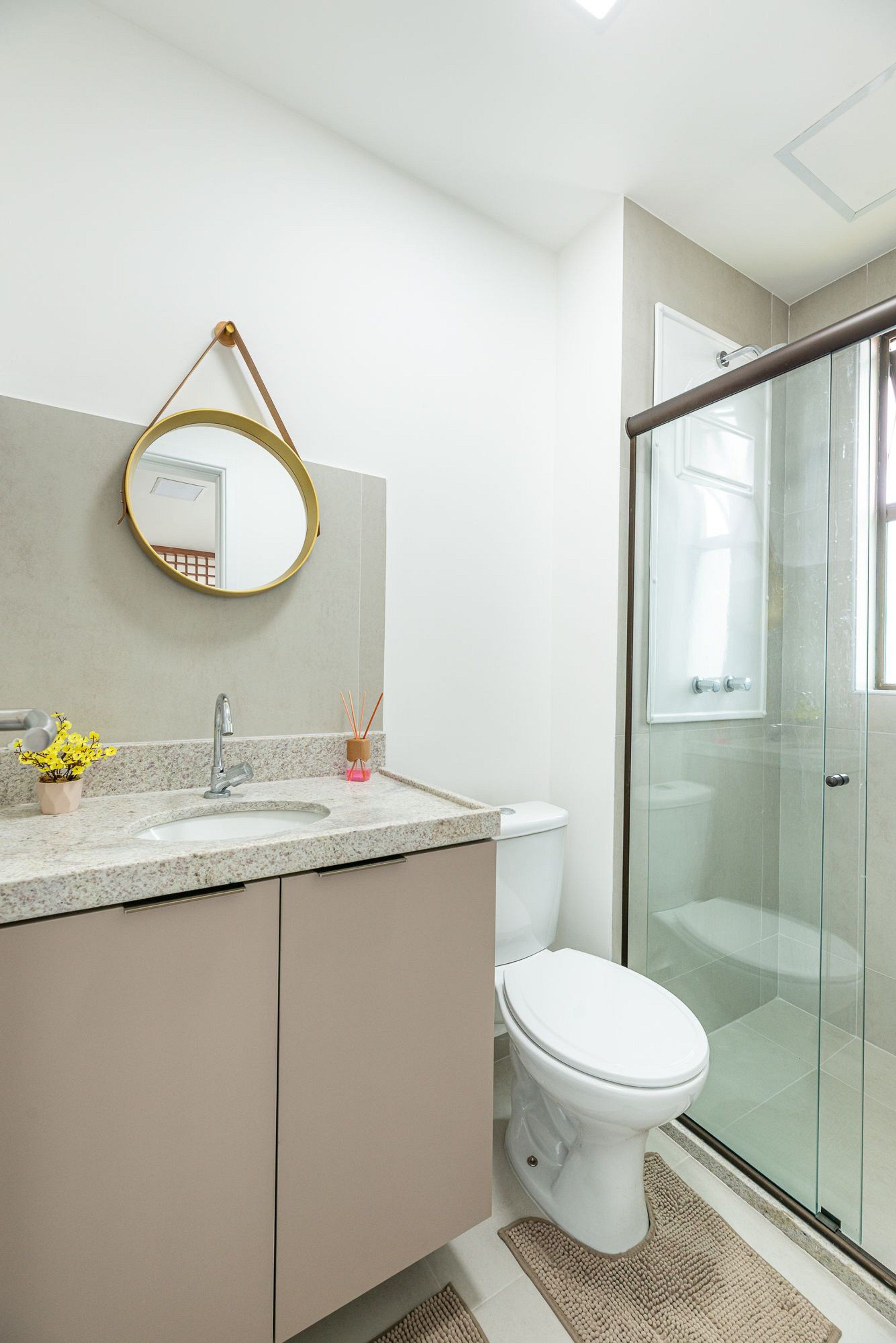 A bathroom with a glass shower enclosure, a white toilet, a sink with a granite countertop, and a mirror with a gold frame.