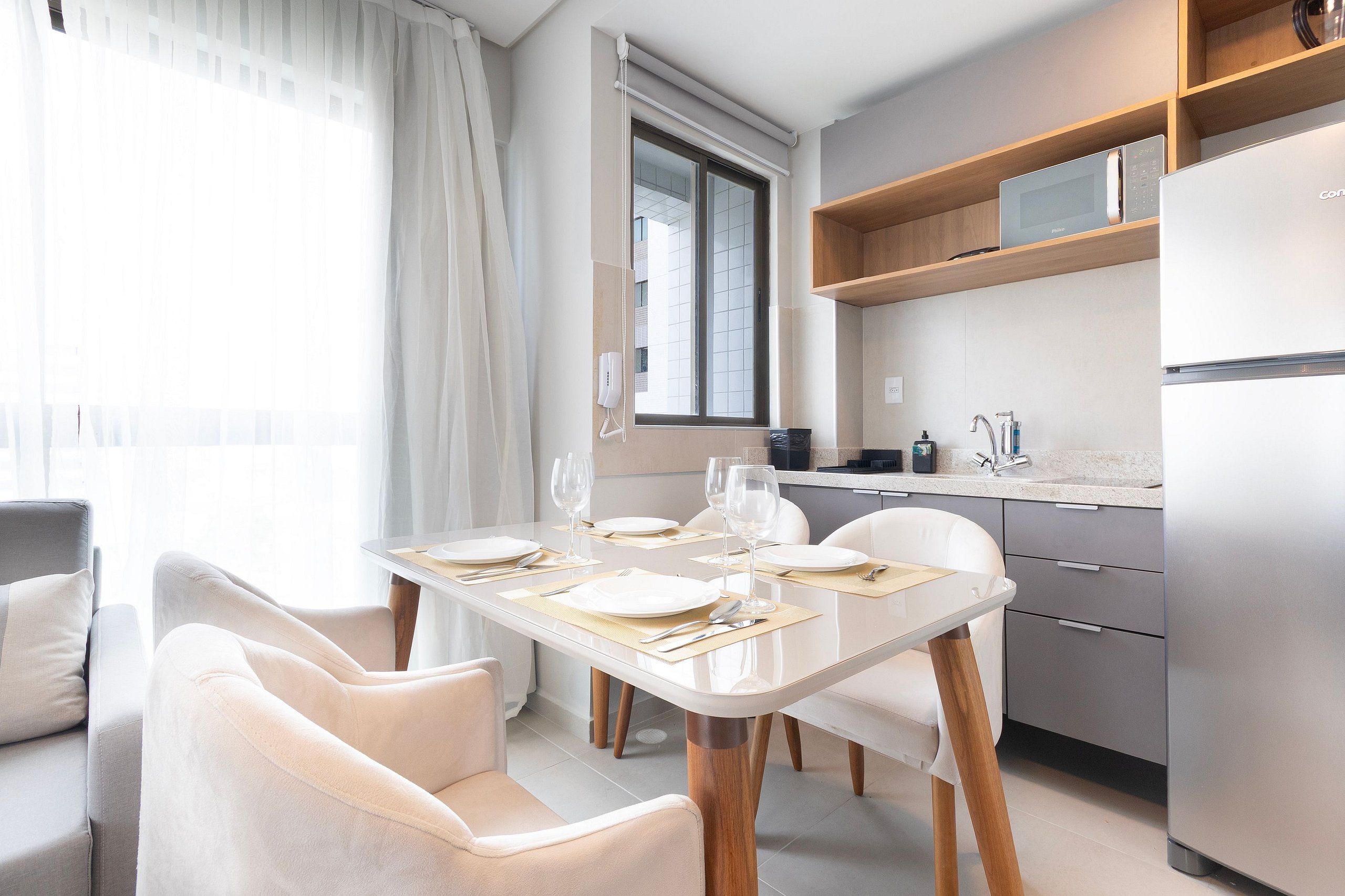 A modern kitchen with a built-in microwave, a refrigerator, and wooden shelves.