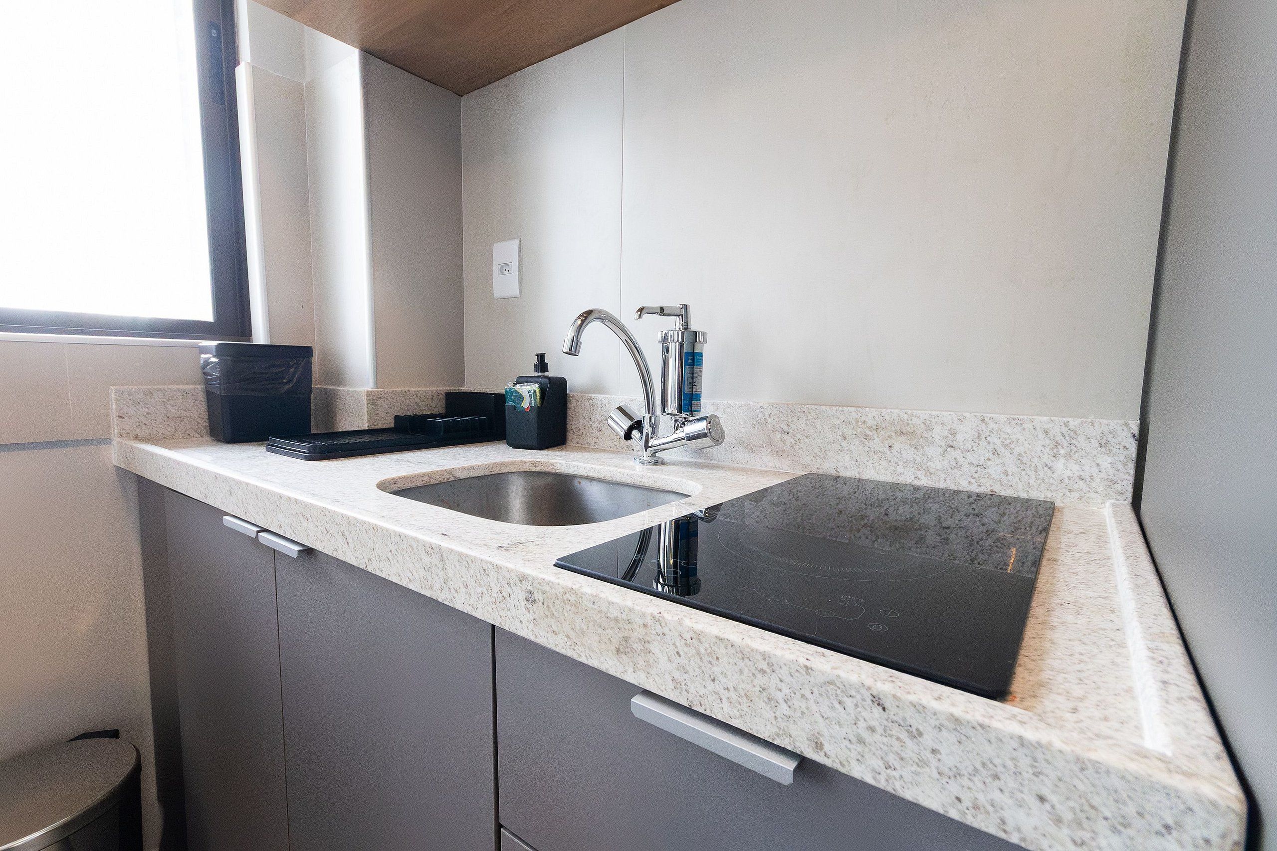 A kitchen with a double sink, a built-in stovetop, and a window providing natural light.