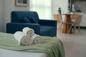 A neatly made bed with rolled white towels and a green blanket. - Botanik With Coworking, Pet Place, and Skyview By Carpediem (Recife)