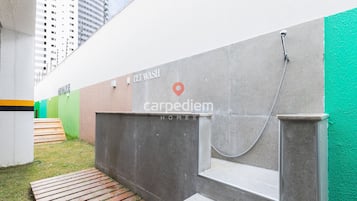 Zona de lavado para mascotas con pared de concreto, manguera metálica y una ventana pequeña.