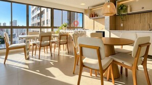 Une cuisine moderne avec une grande fenêtre, des chaises en bois et un luminaire suspendu.