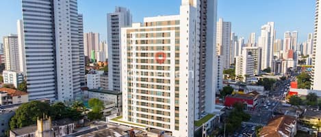 Un edificio alto con un logotipo rojo destacado, rodeado de otros edificios altos en un paisaje urbano.