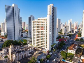 A high-rise building with a prominent red logo, surrounded by other tall buildings in a cityscape. - Botanik With Coworking, Pet Place, and Skyview By Carpediem (Recife)