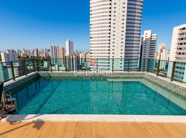 Una piscina en la azotea con vistas a un paisaje urbano, rodeada de edificios altos.