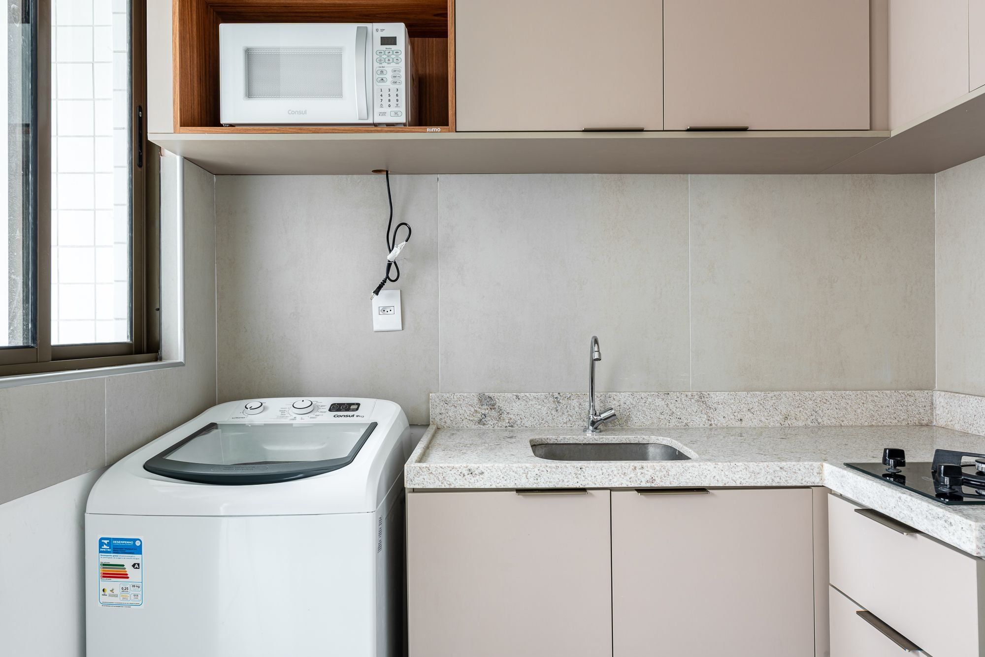Cocina compacta con lavadora, microondas y lavamanos.