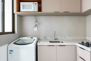 A compact kitchen with a washing machine, a microwave, and a sink.