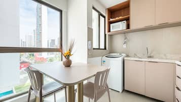 Une cuisine moderne avec une table à manger, des chaises, un lave-linge et une vue sur la ville grâce à de grandes fenêtres.