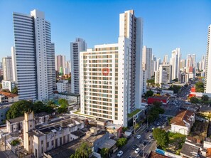 Un edificio alto con un logotipo rojo destacado, rodeado de otros edificios altos en un paisaje urbano.