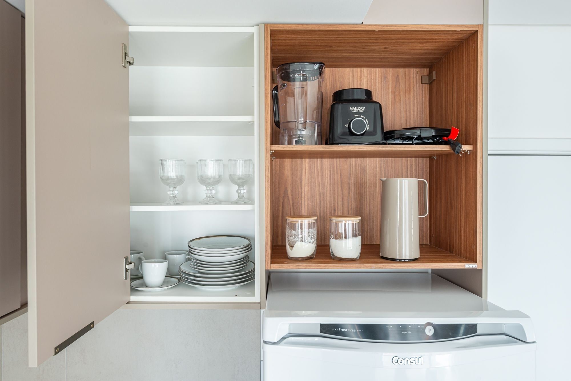 A kitchen with a built-in appliance, a coffee maker, and storage shelves.