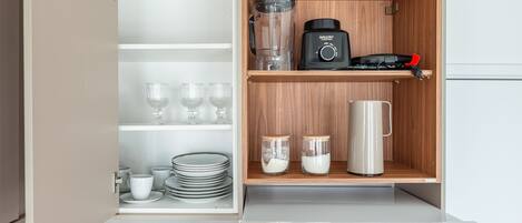 A kitchen with a built-in appliance, a coffee maker, and storage shelves.
