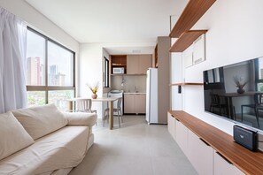 A modern apartment with a living area, kitchenette, and a large TV. - Botanik With Coworking, Pet Place, and Skyview By Carpediem (Recife)
