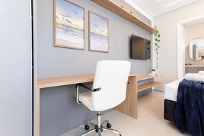 A modern room with a white office chair, a TV mounted on the wall, and a bed with a blue blanket. - Botanik With Coworking, Pet Place, and Skyview By Carpediem (Recife)